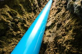 Bright blue pipe running through a dirt trench or excavation site