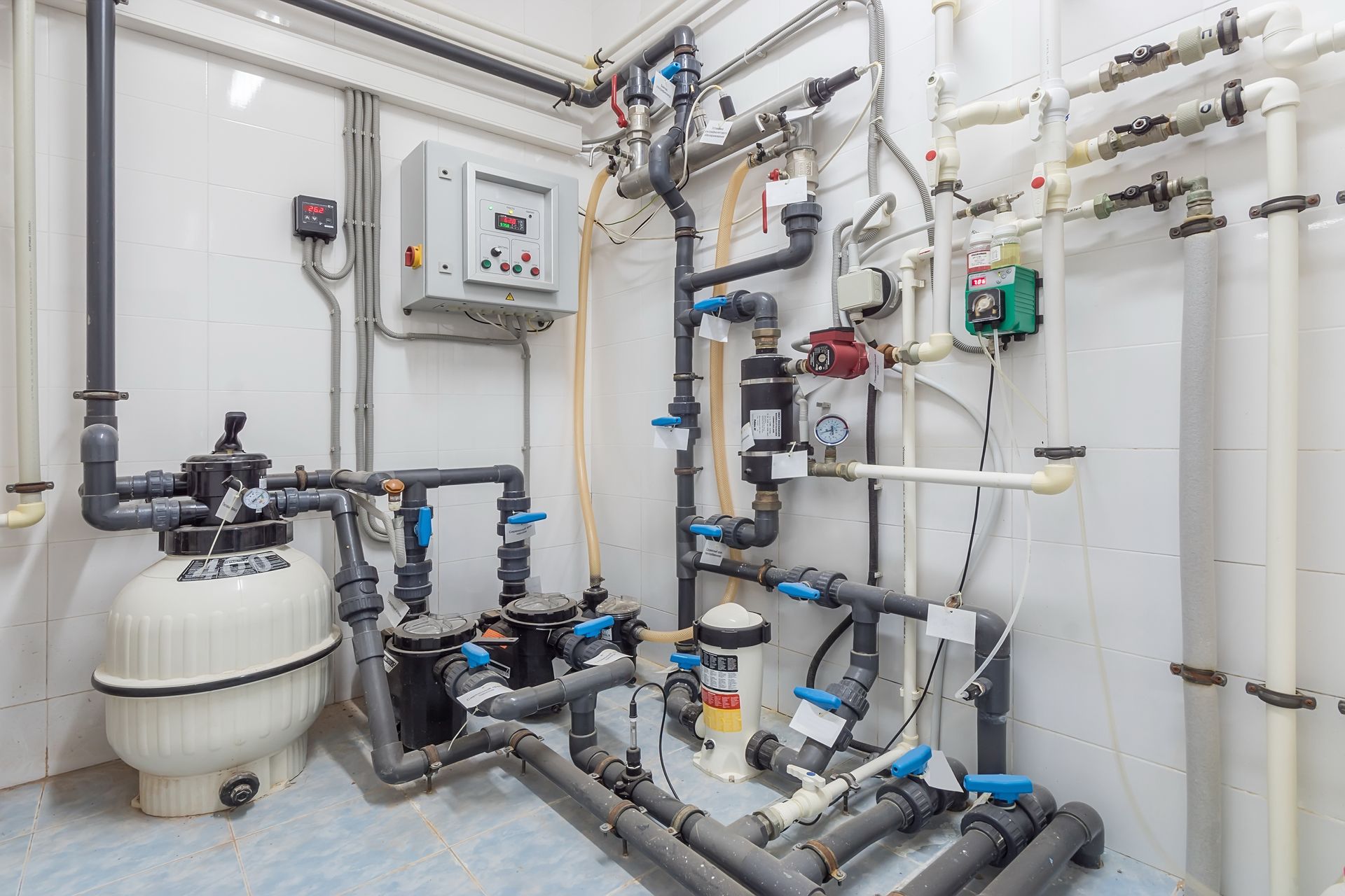 Industrial water treatment equipment with pipes, tanks, valves, and control panel in a utility room