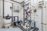 Industrial water treatment equipment with pipes, tanks, valves, and control panel in a utility room