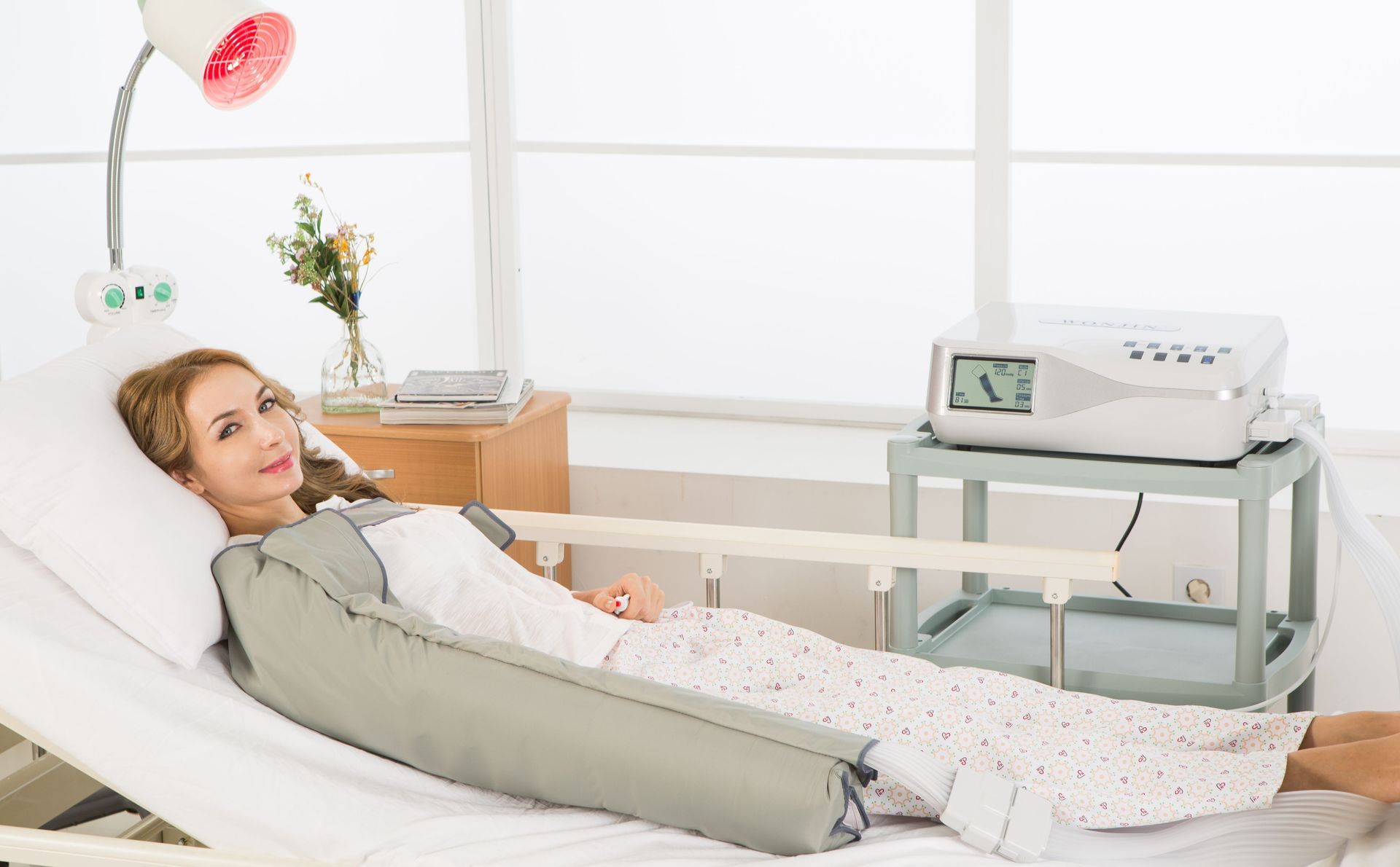 Eine Frau liegt mit einer Maschine an ihren Beinen in einem Krankenhausbett.