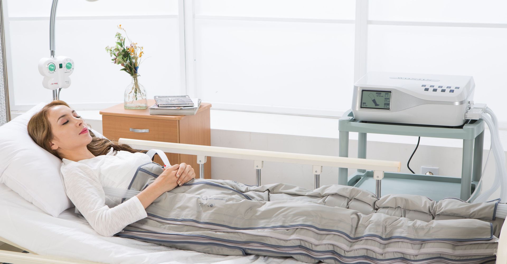 Eine Frau liegt mit einer Decke auf dem Bauch in einem Krankenhausbett.
