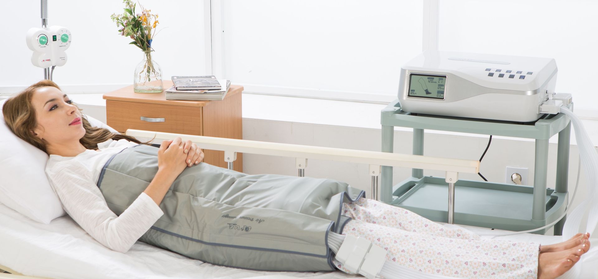 Eine Frau liegt mit einer Maschine an ihren Beinen in einem Krankenhausbett.