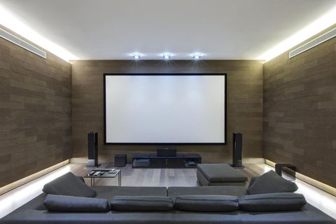 Modern home theater with a large screen, speakers, and a sectional sofa.