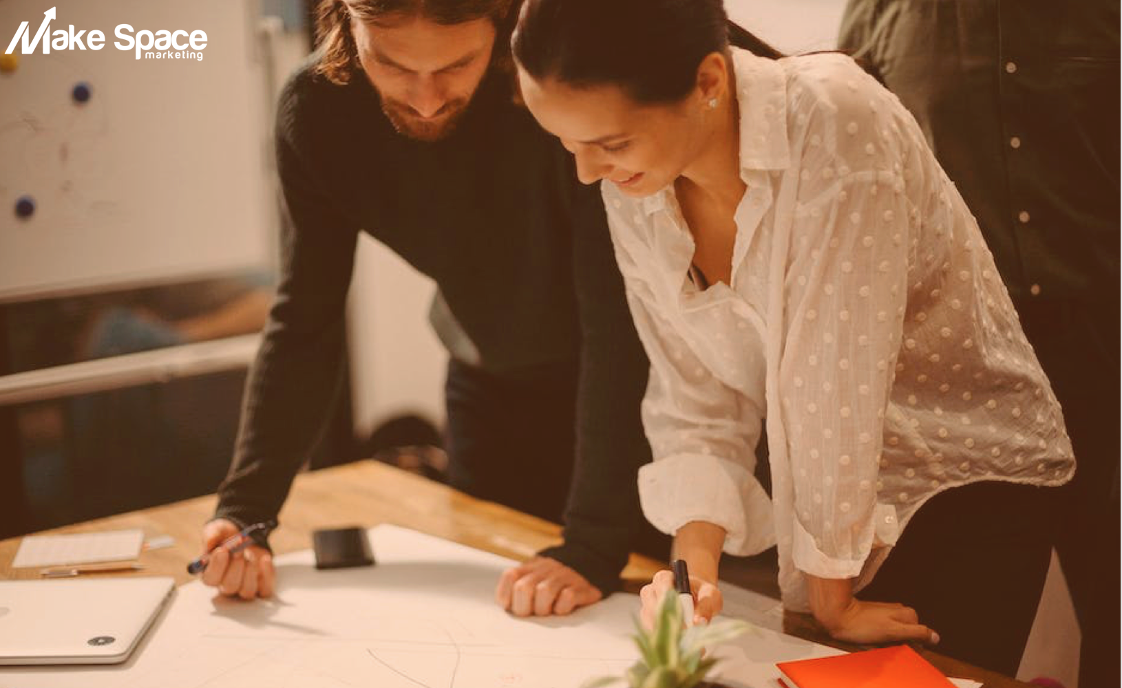 A man and a woman are looking at a piece of paper on a table.