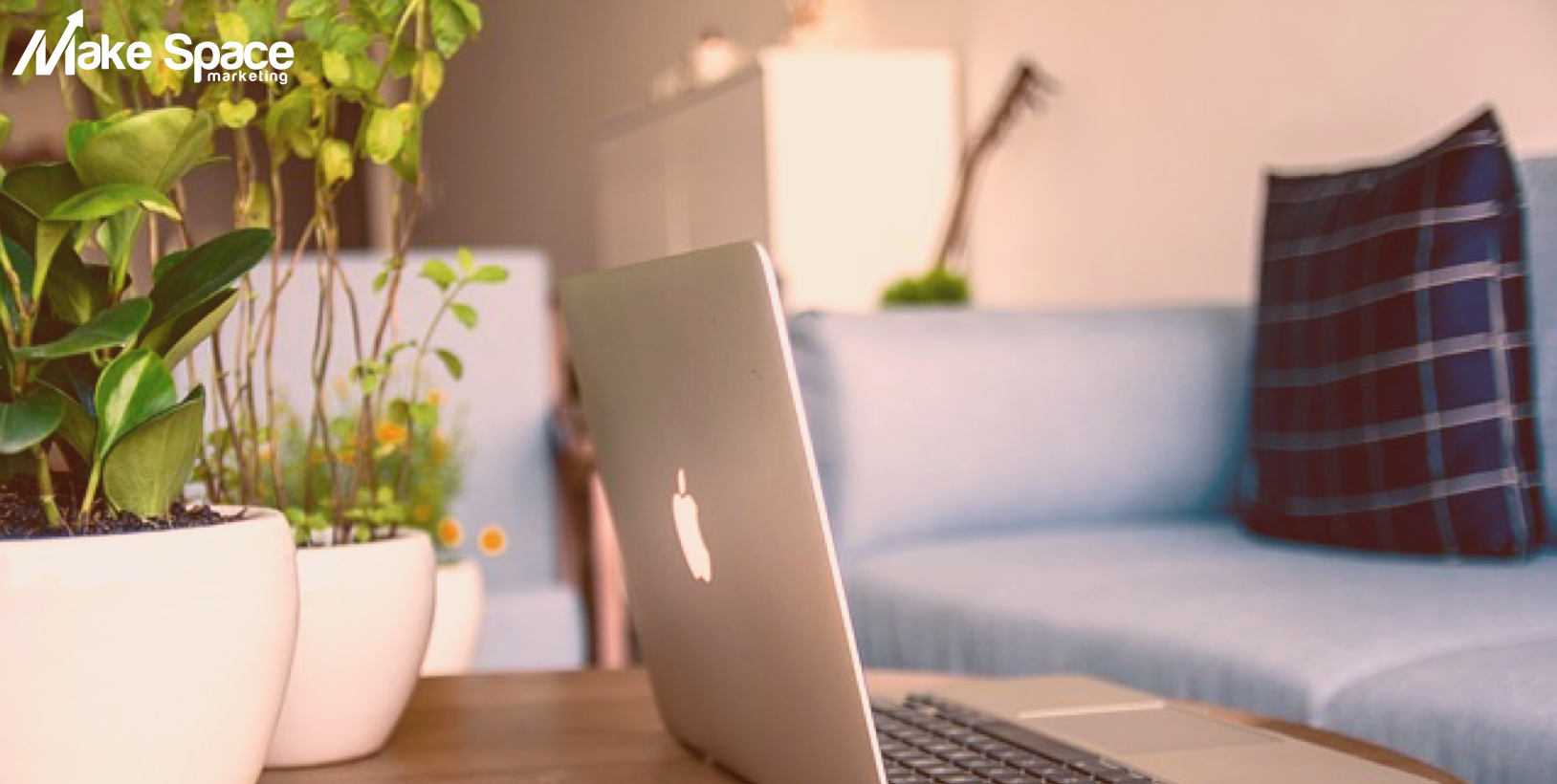 A laptop computer is sitting on a table in front of a couch.