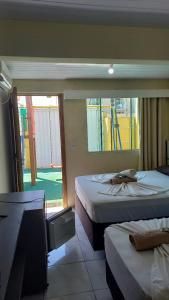 Quarto pequeno com duas camas, piso de azulejo e porta de correr que dá para uma varanda.
