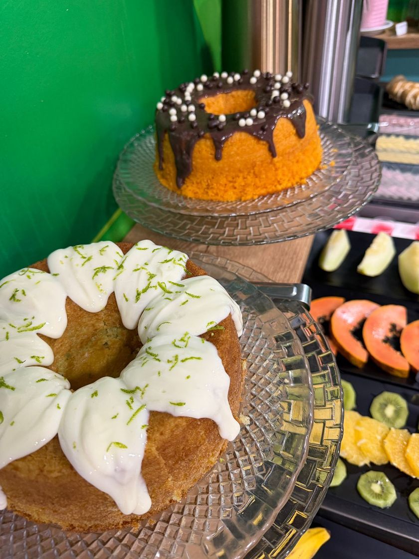 Dois bolos Bundt decorados em suportes de vidro, um com cobertura de chocolate e granulado, o outro com cobertura branca.