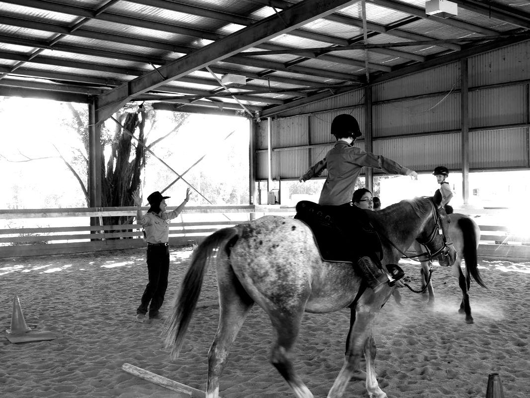 A black and white photo of a person riding a horse in a barn.