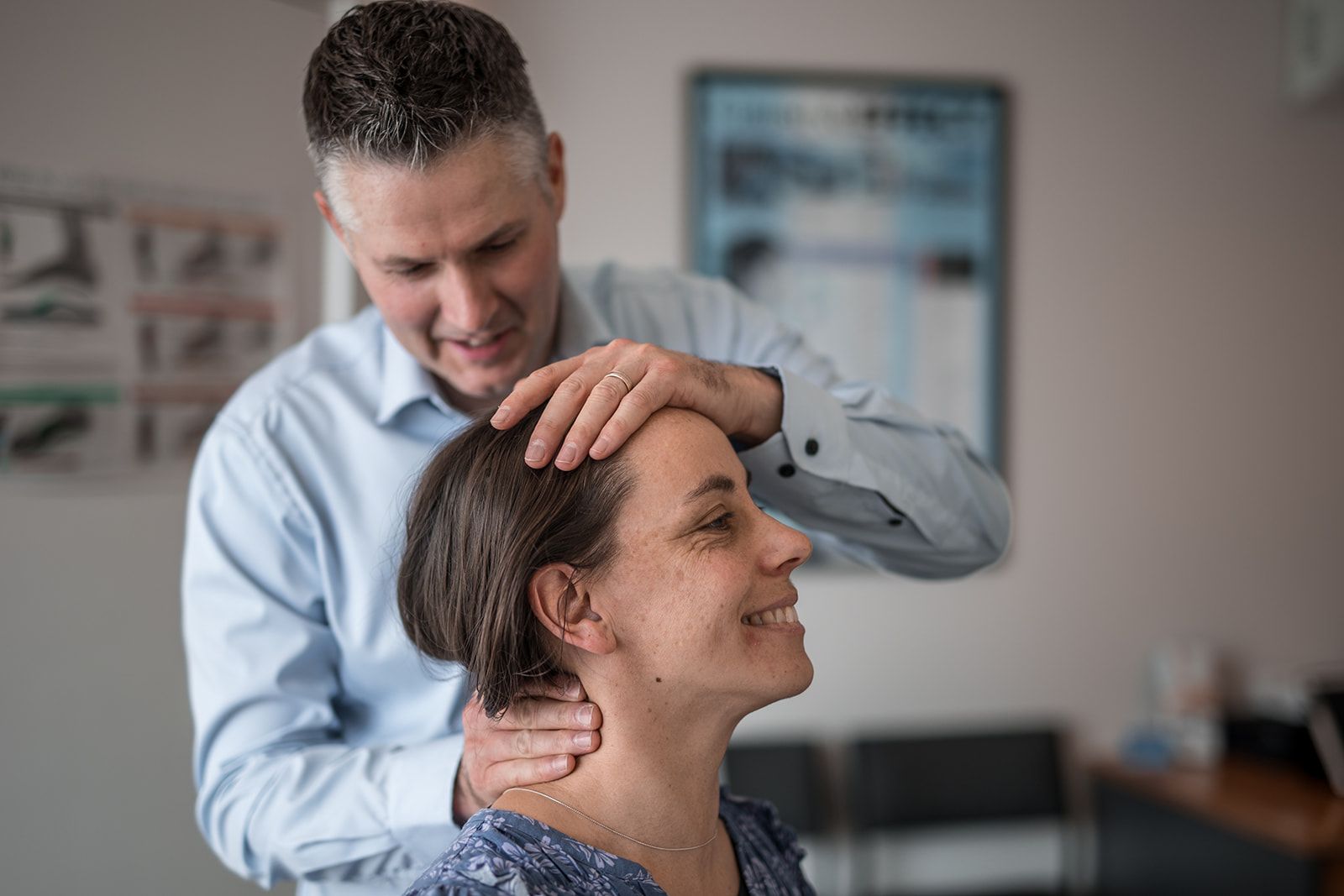 A man is examining a woman 's neck and smiling.