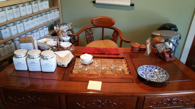 Tea service on a wooden table with white canisters, teapot, cups, and a blue-patterned bowl in a traditional room