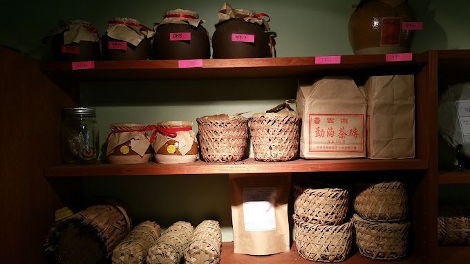 Wooden shelves lined with woven baskets, jars, and packaged goods in a dimly lit pantry.
