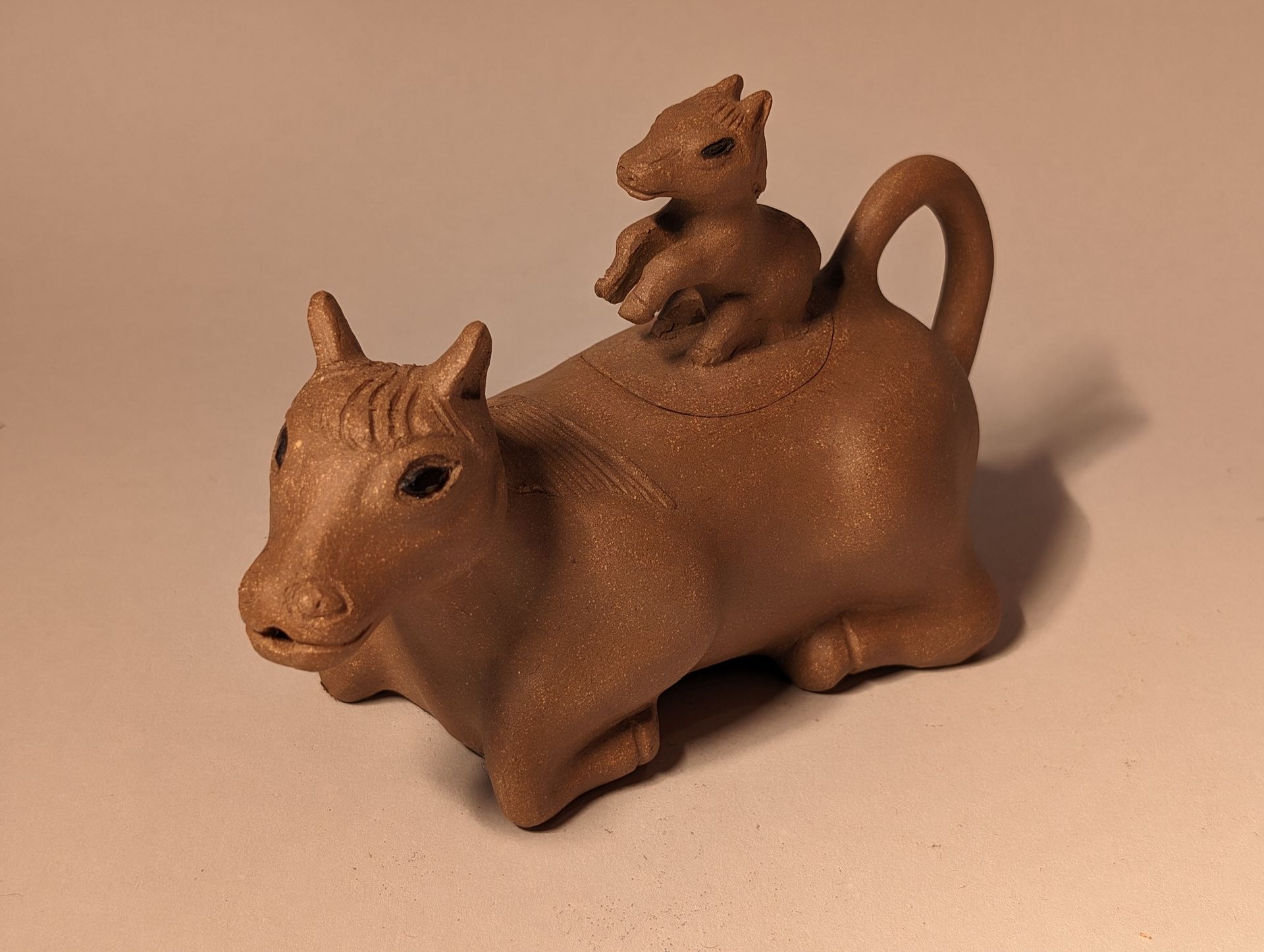 Small brown ceramic animal figurine with a rider sitting on its back