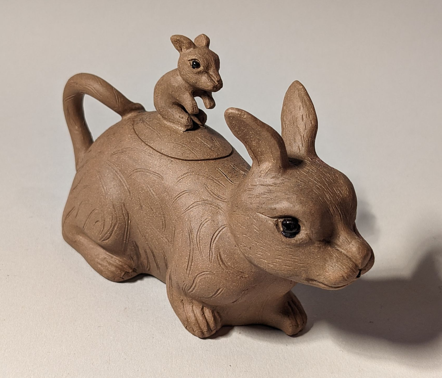 Brown ceramic kangaroo figurine with a joey on its back, against a plain background