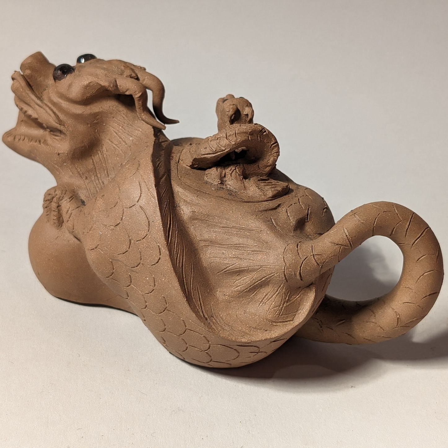 Small brown ceramic teapot shaped like an animal, with a round handle and textured surface