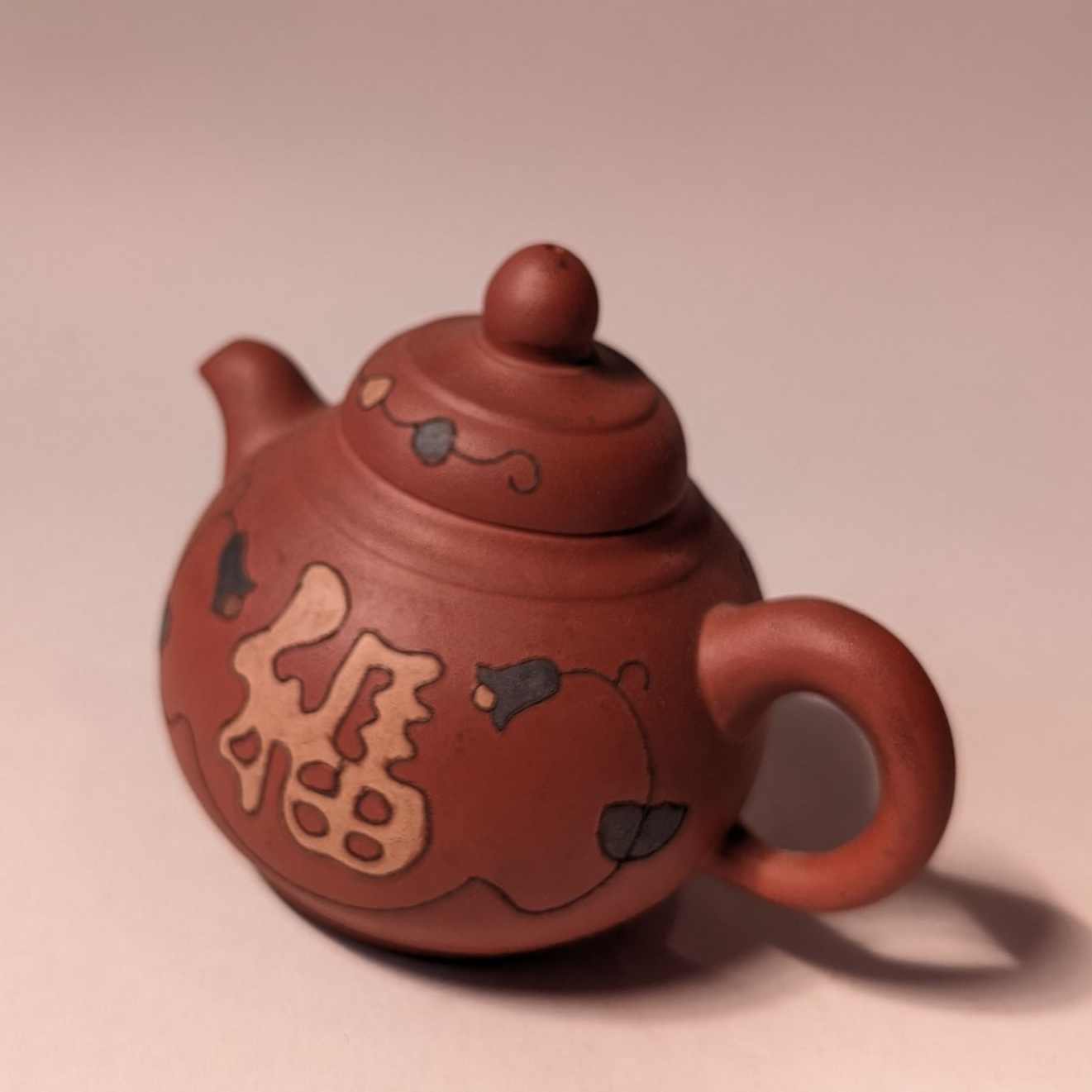 Red teapot with Chinese characters on a plain background