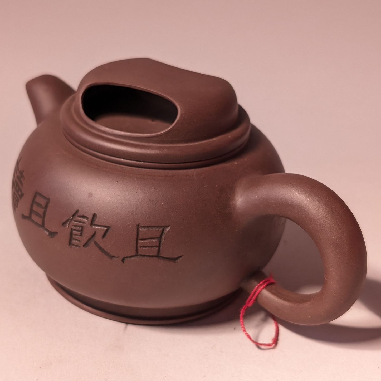 Brown ceramic teapot with a round handle and Chinese characters on the side