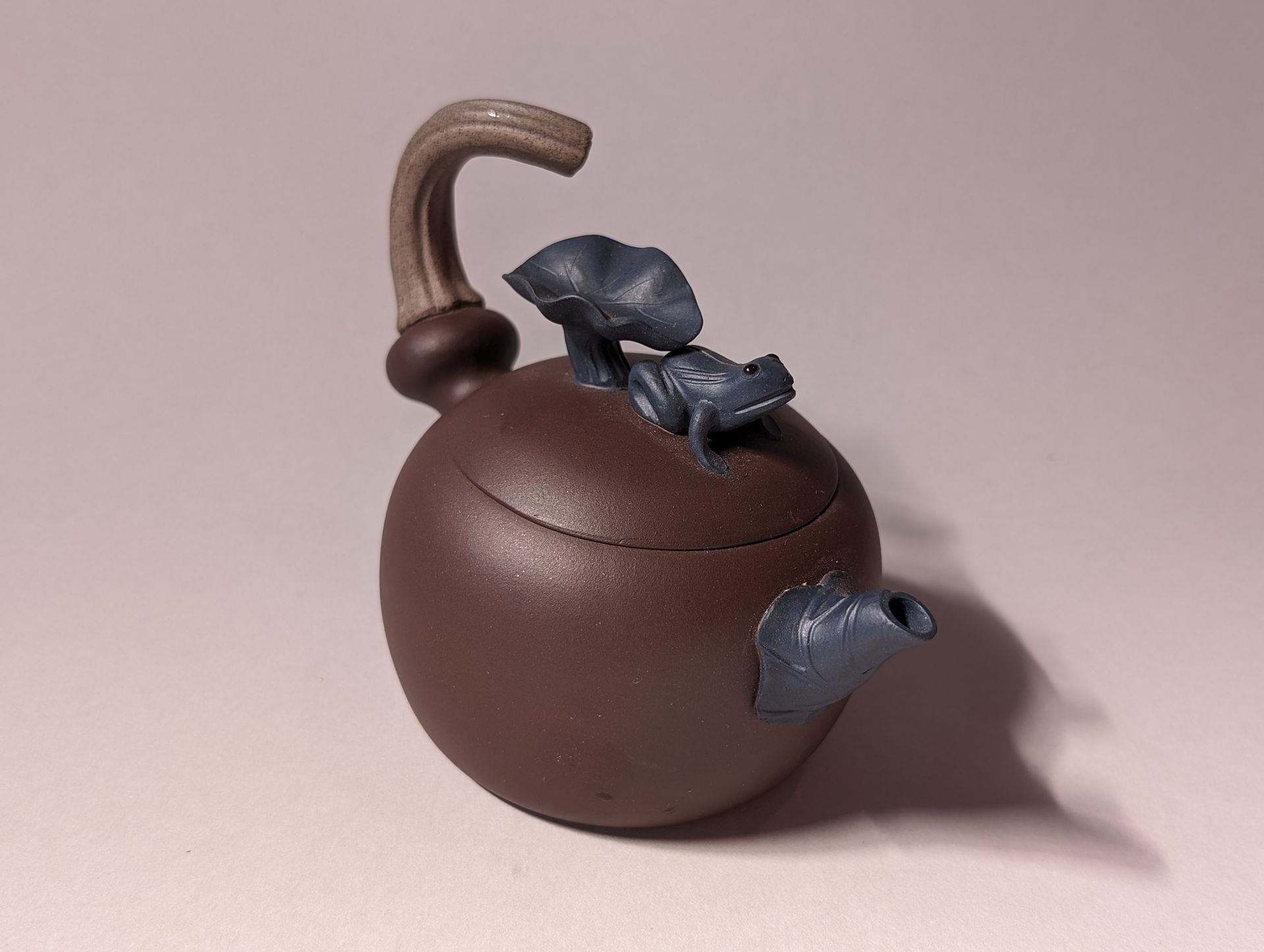 Brown decorative sphere with a curved handle and small leaf-like accents on top and side