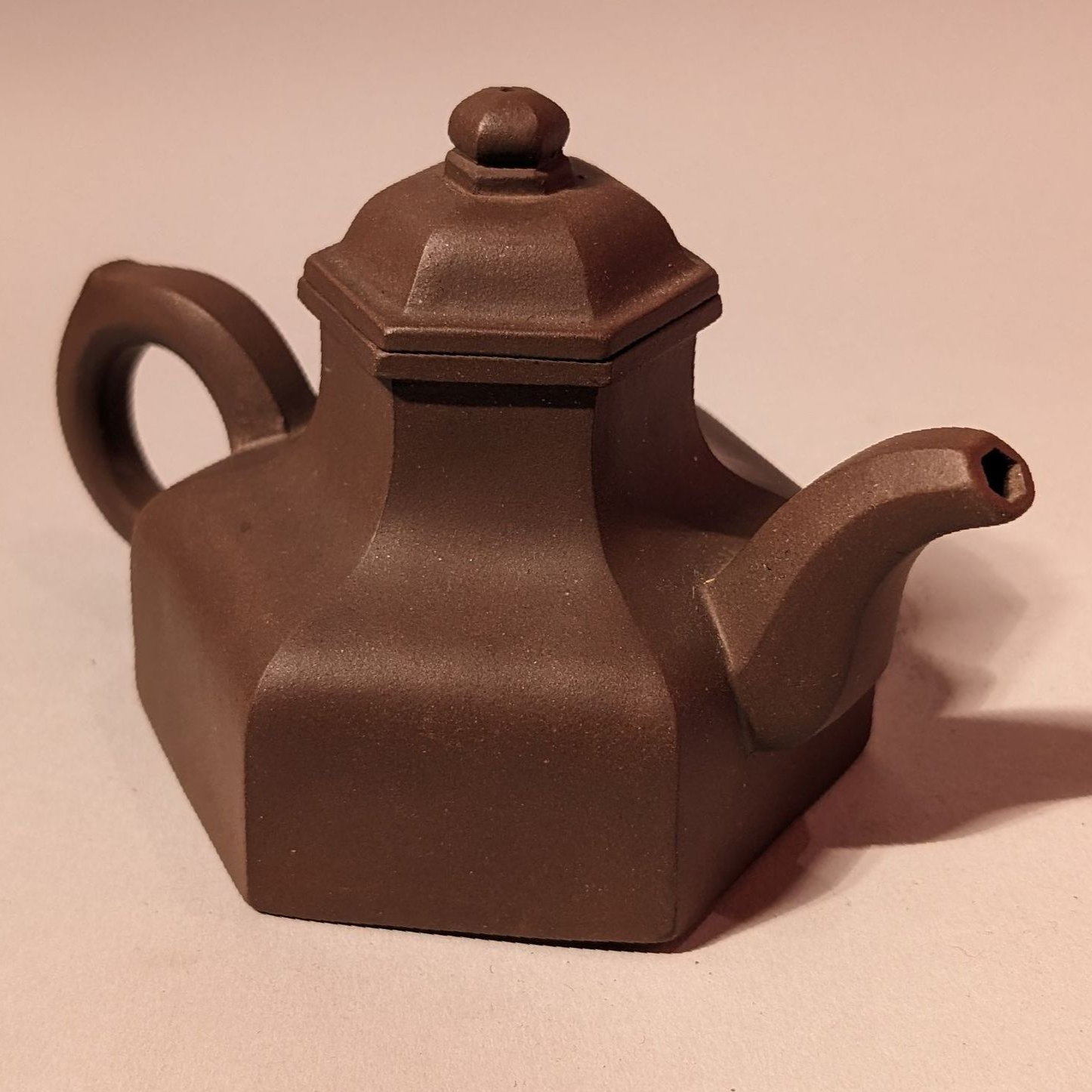 Small brown teapot with a hexagonal body and lid, shown on a plain background.