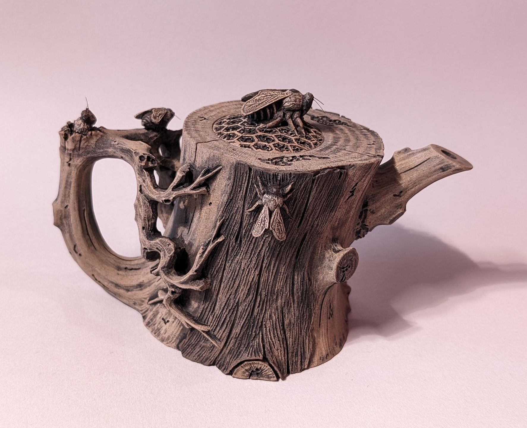 A small rustic wooden teapot with a handle and spout on a light background.