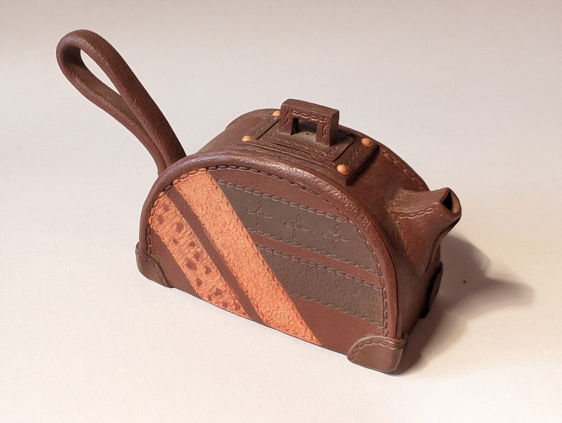 Small brown leather handbag with a looped strap and tan diagonal stripe on a white background