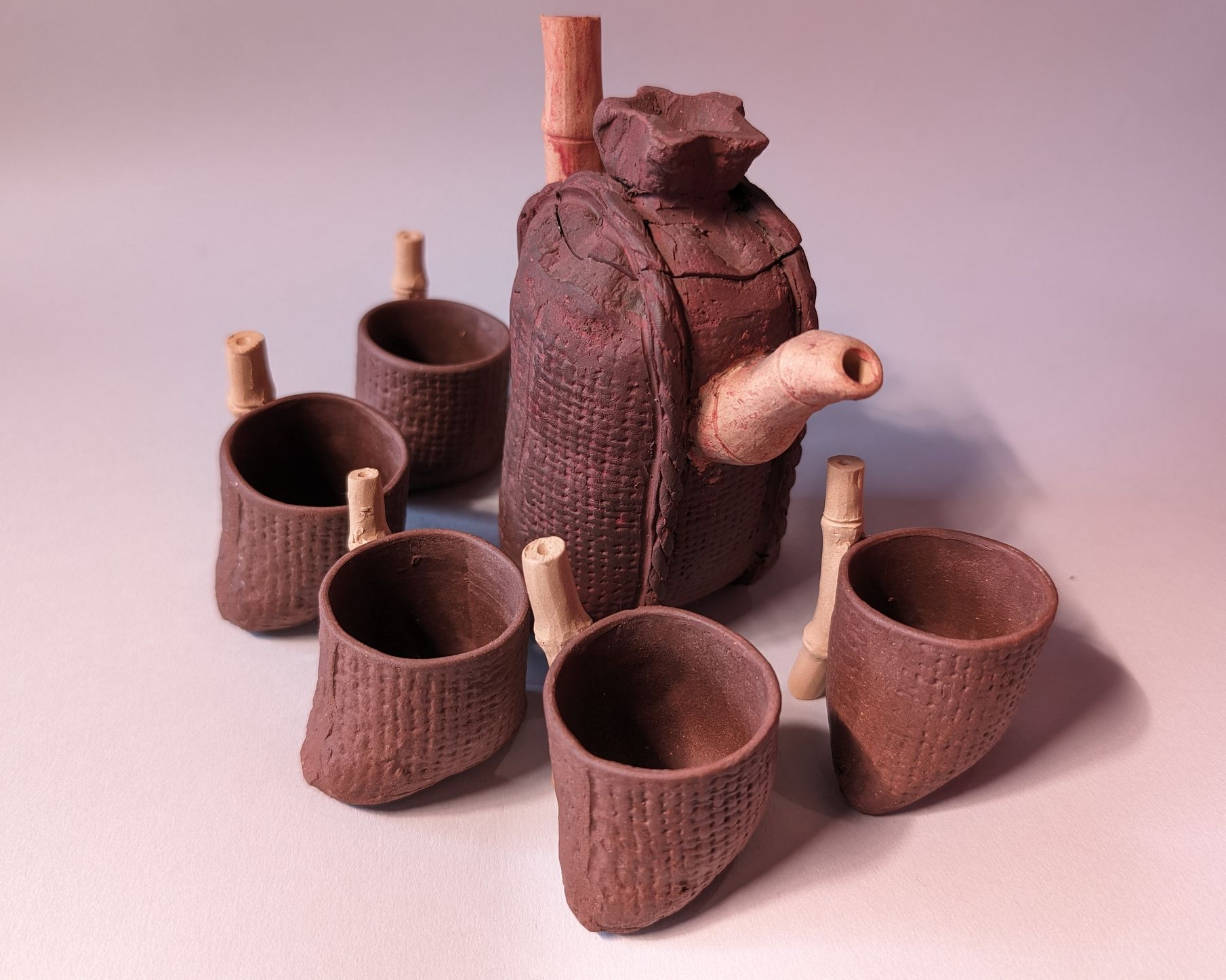 Brown ceramic tea set with a teapot and five cups on a light background