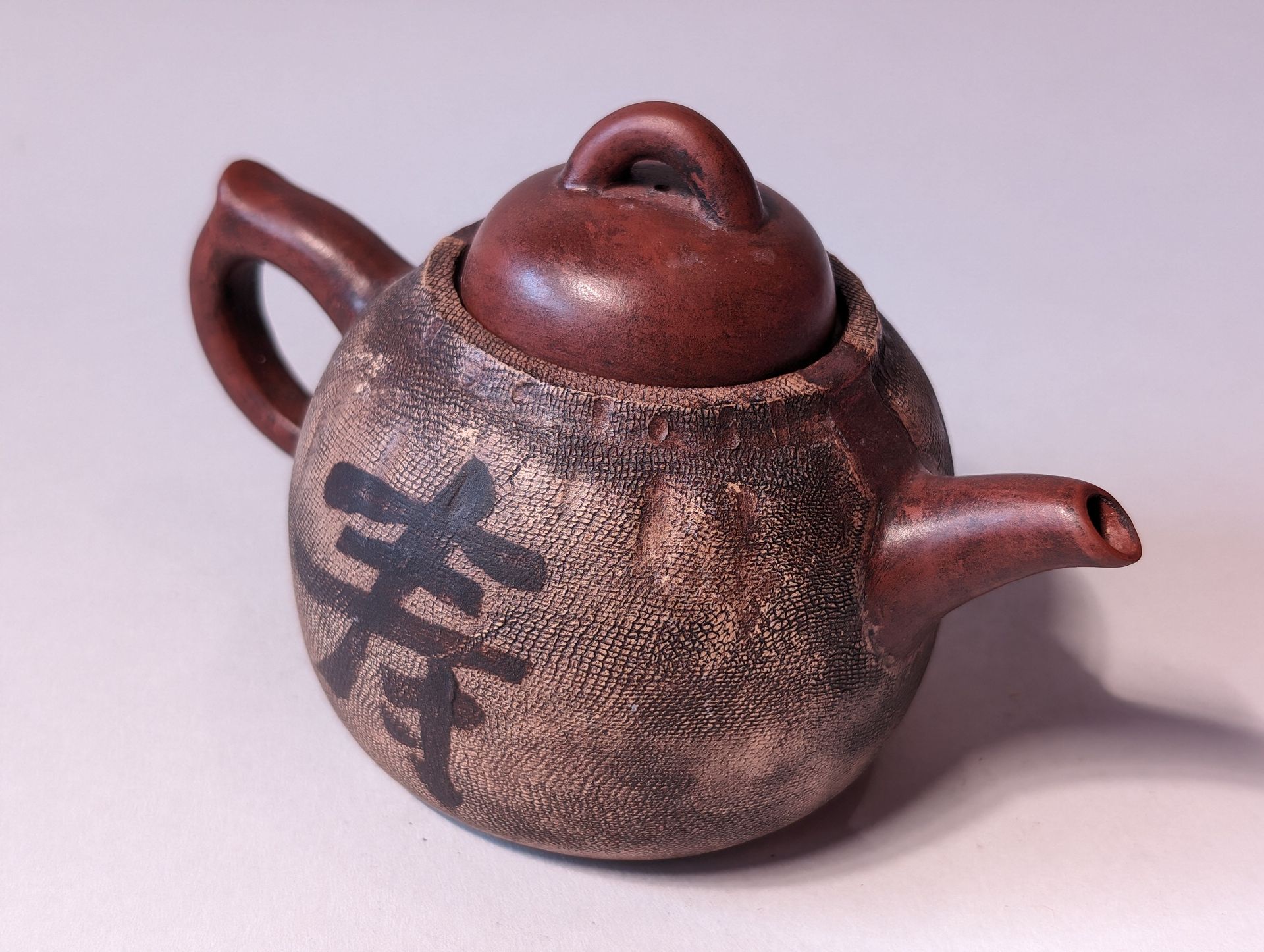 Brown teapot with lid and calligraphy character on the side, isolated on a white background