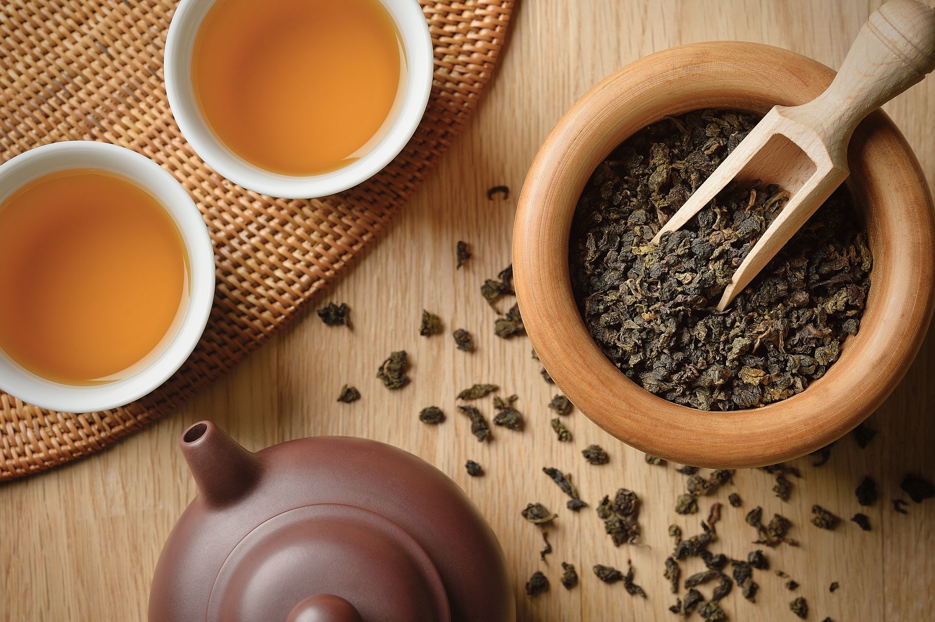 Tea set with two cups, a teapot, and loose tea leaves on a wooden table