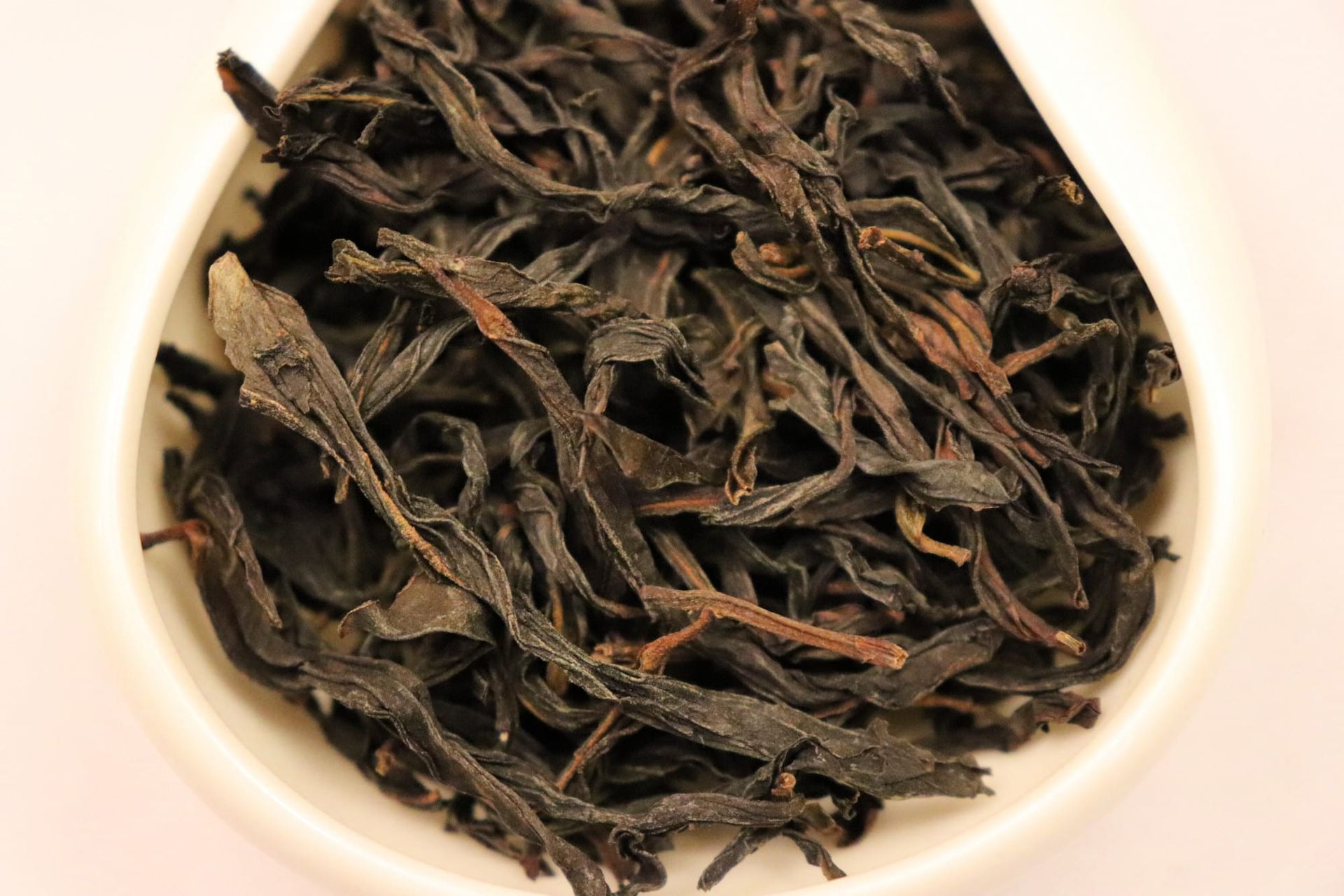 Loose dark tea leaves in a white bowl