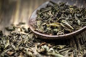 A spoonful of loose dried tea leaves on a rustic wooden surface