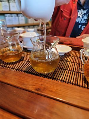 Tea being poured into glass teacups on a wooden table at a cafe
