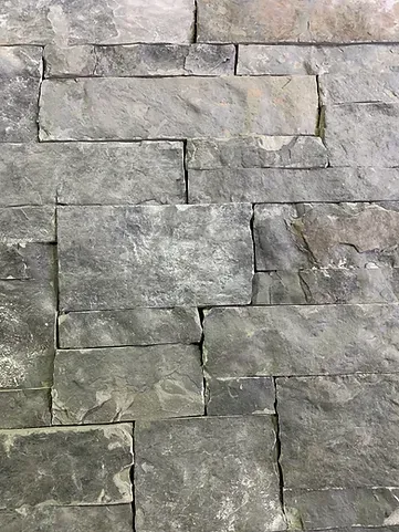 Close-up of a wall made of gray rectangular stone tiles with irregular edges.
