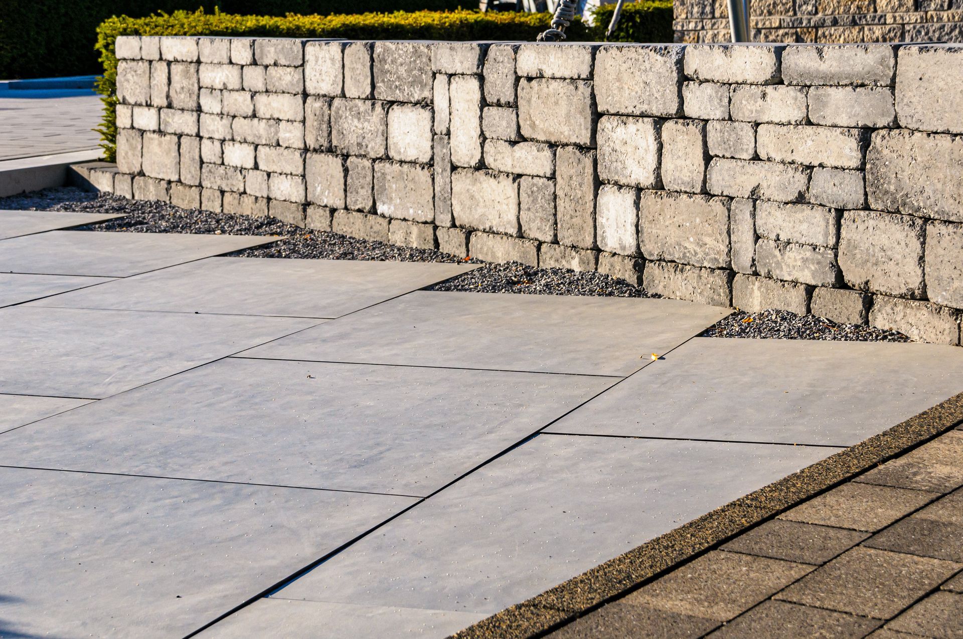 Outdoor pavers beside a textured stone retaining wall