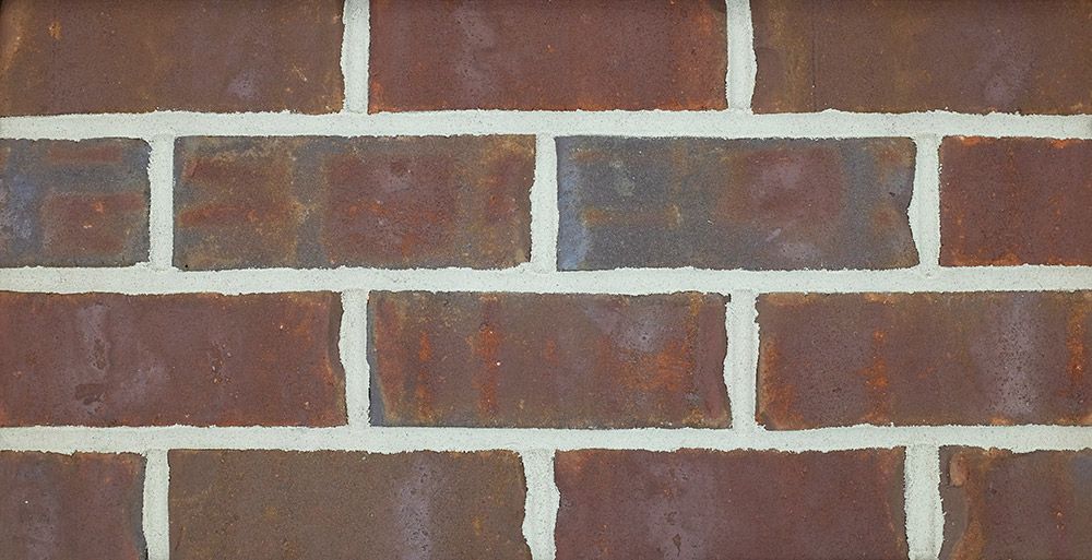 Close-up of a brick wall with red-brown bricks and white mortar.