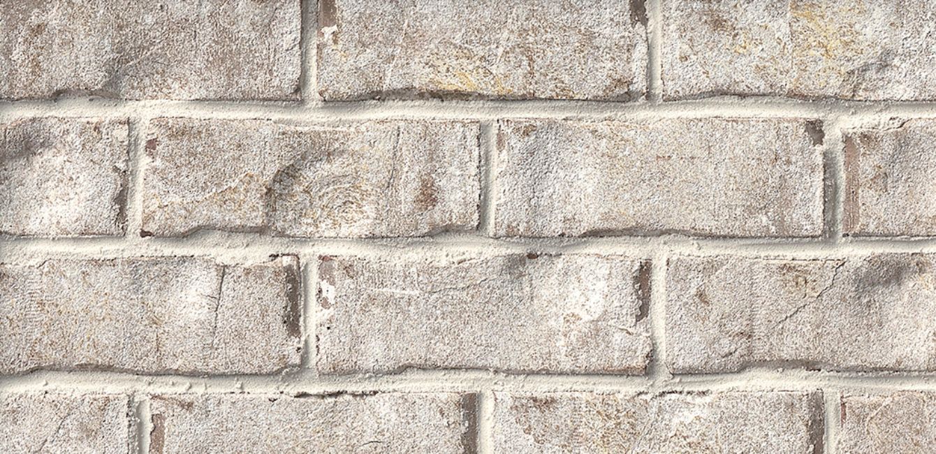 Close-up of a weathered brick wall, light gray and beige with visible mortar lines.