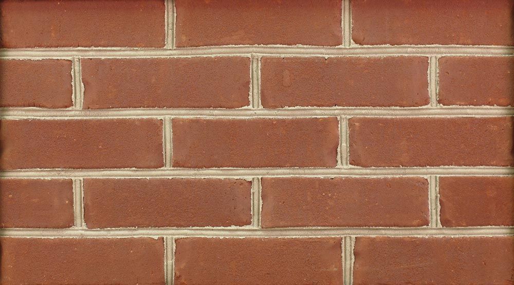 Red brick wall with light-colored mortar between the bricks.