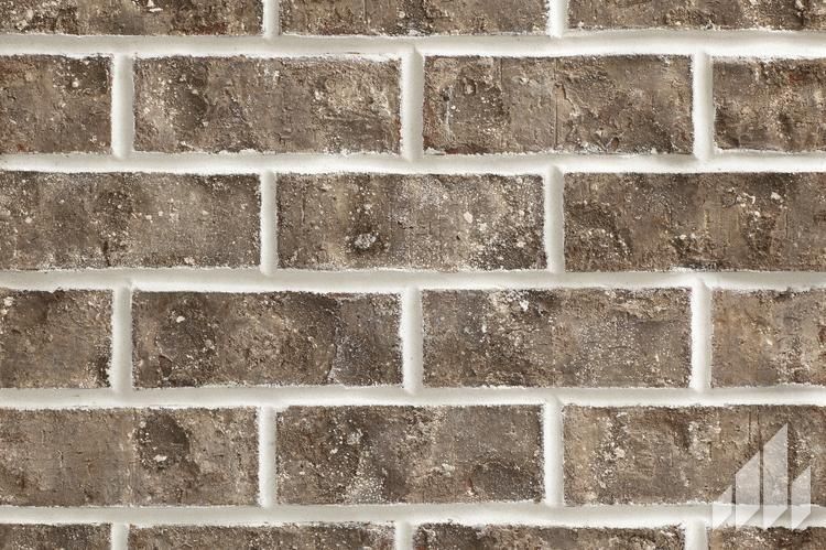 Close-up of a brick wall with varied brown bricks and white mortar.