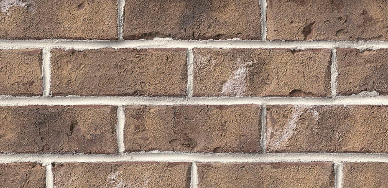 Close-up of a brown brick wall with white mortar.