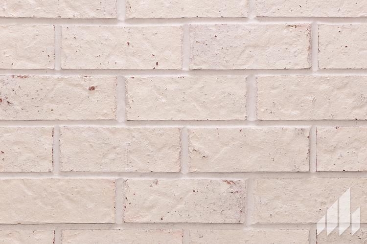 Close-up of a brick wall, beige bricks with white mortar.