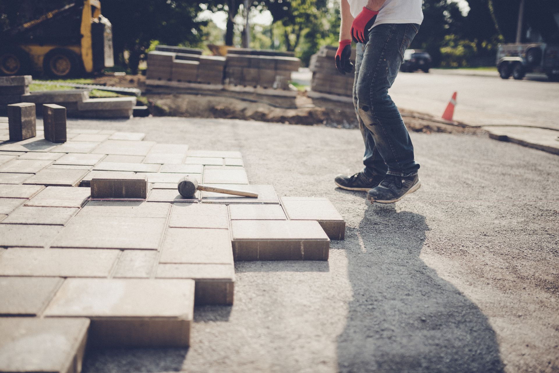 Man installing paving stones for a driveway, expert landscaping paver supplier at work.