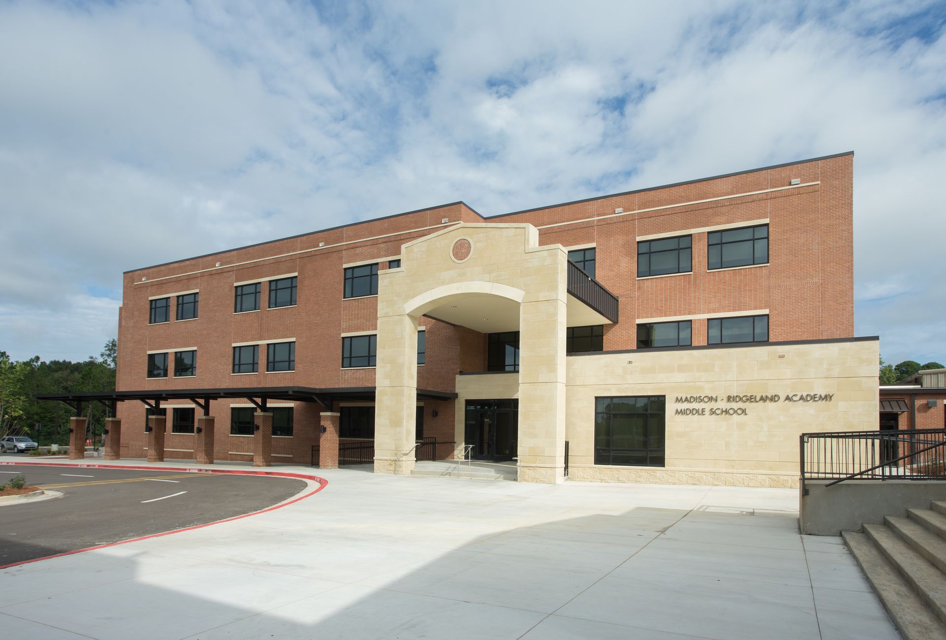 Three-story brick building with a light-colored arched entrance. 