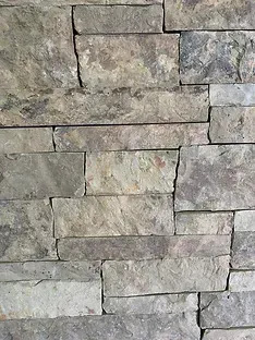 Close-up of a stone wall with rectangular, multi-toned gray and tan blocks.