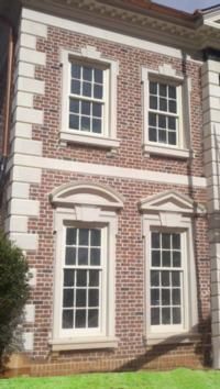 Two-story brick building with white window frames and trim. Two pairs of windows, one arched.