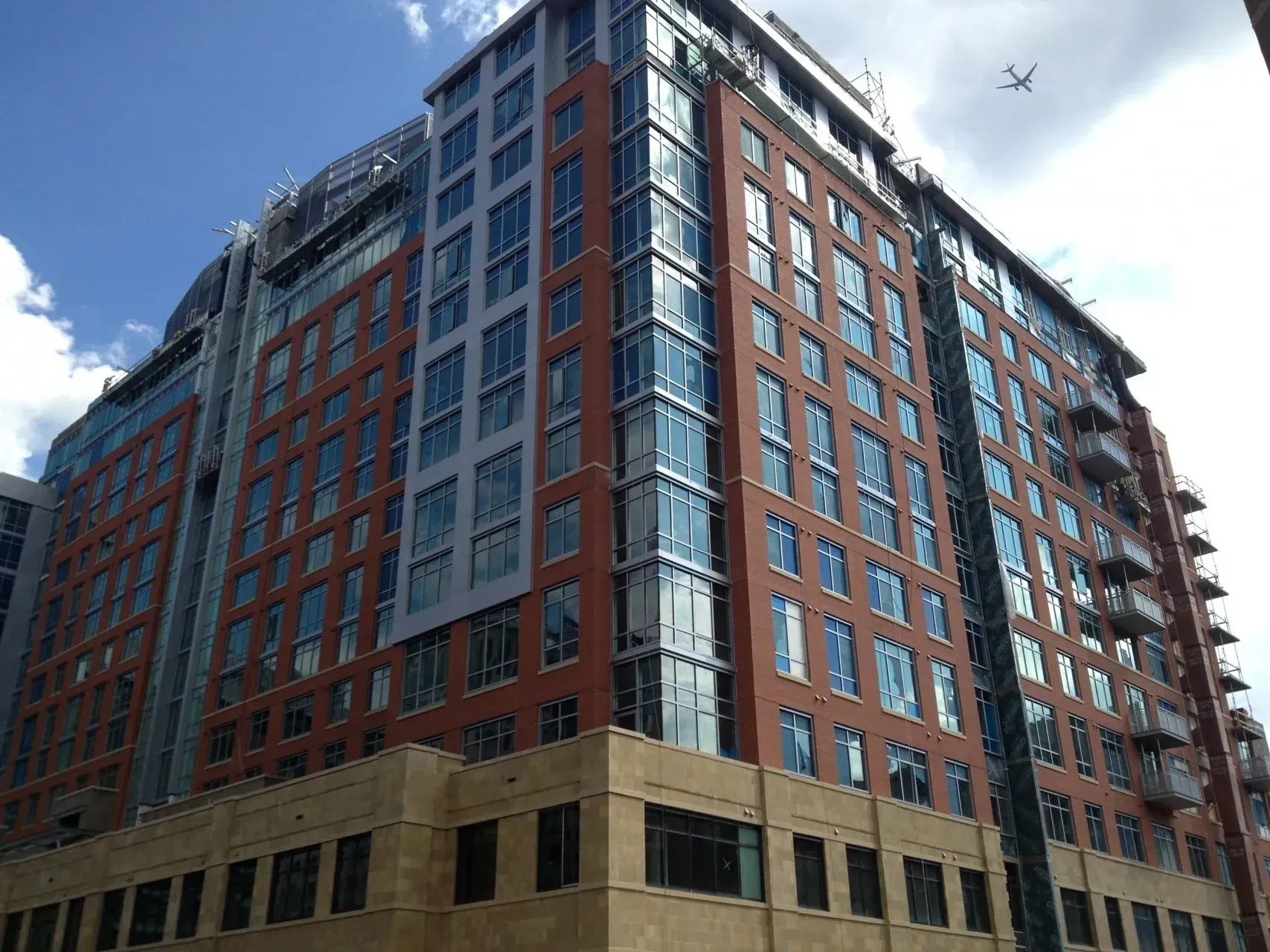 Multistory brick and glass building against a partly cloudy blue sky.