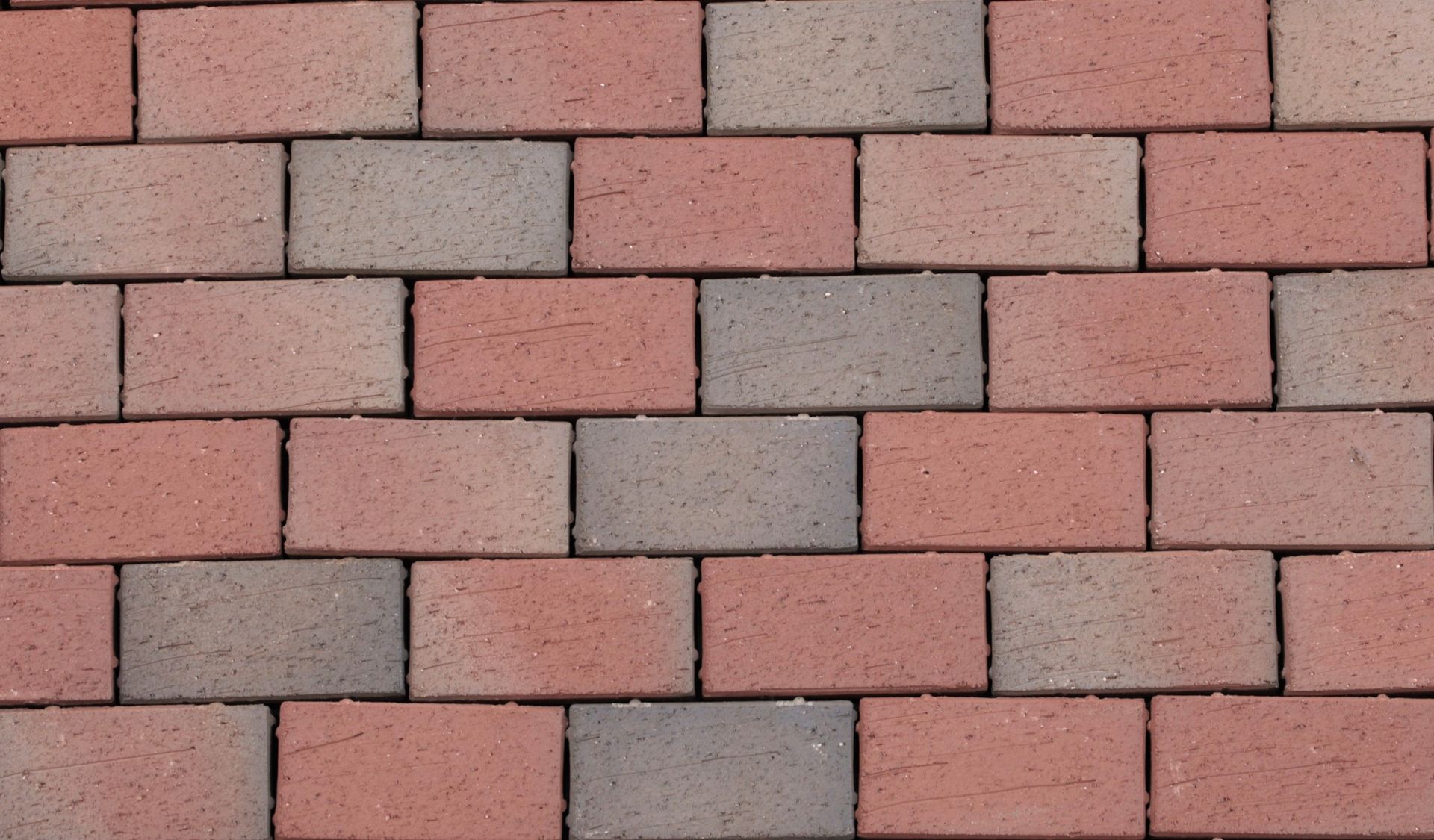 Red and gray brick patio arranged in a running bond pattern.