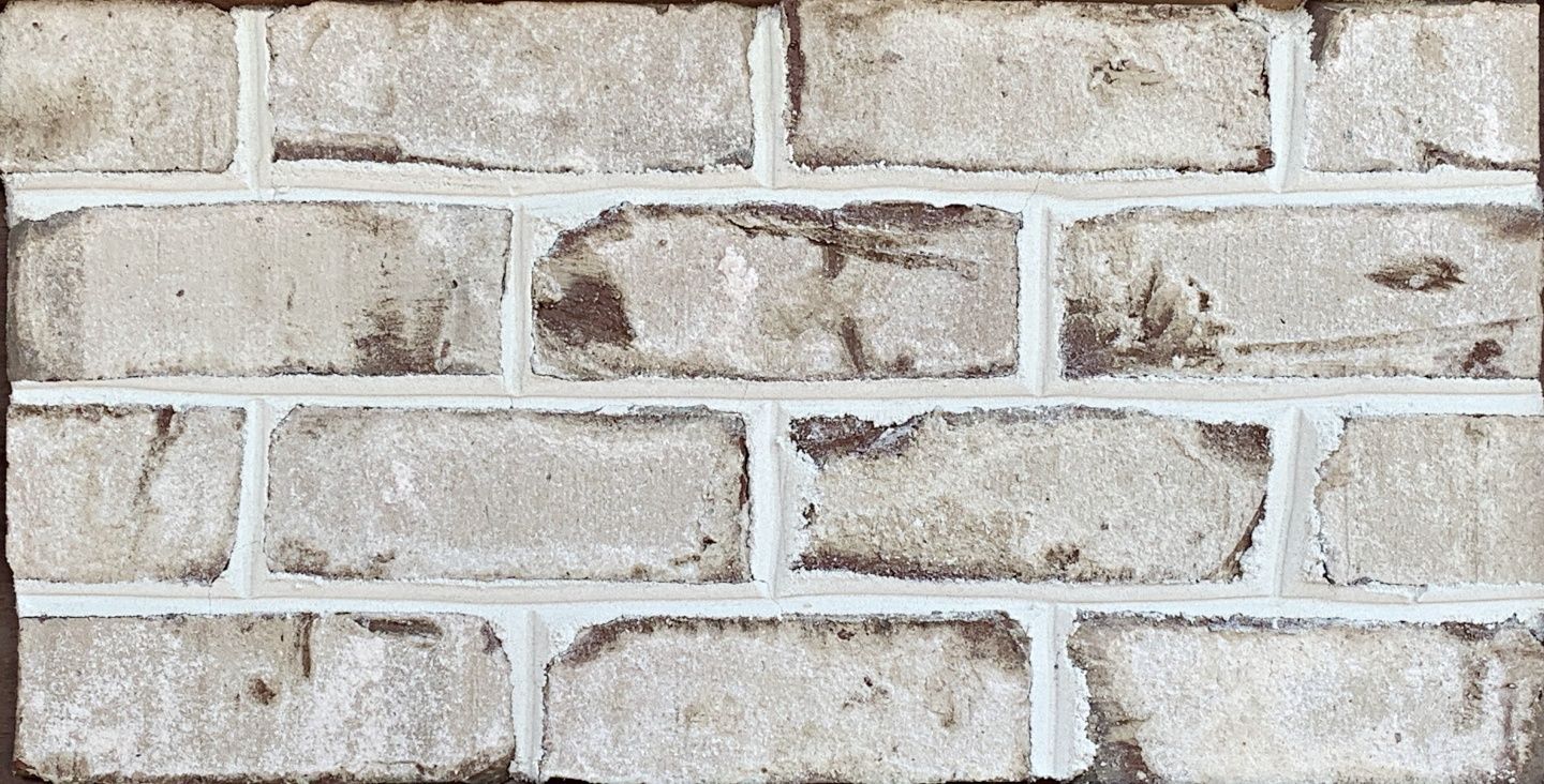 Whitewashed brick wall with dark brown accents and white mortar.