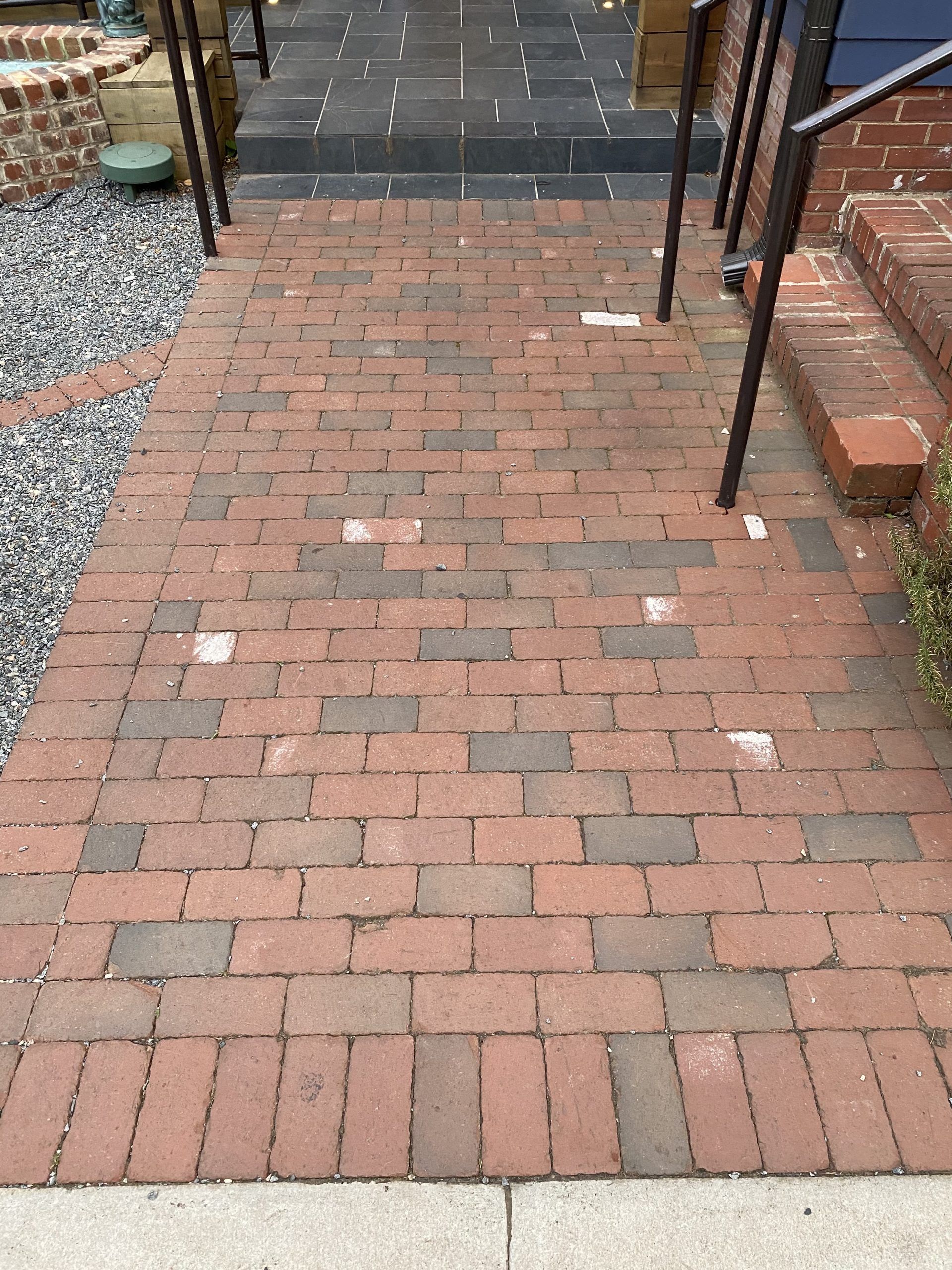 Brick pathway leading to steps with black railing.