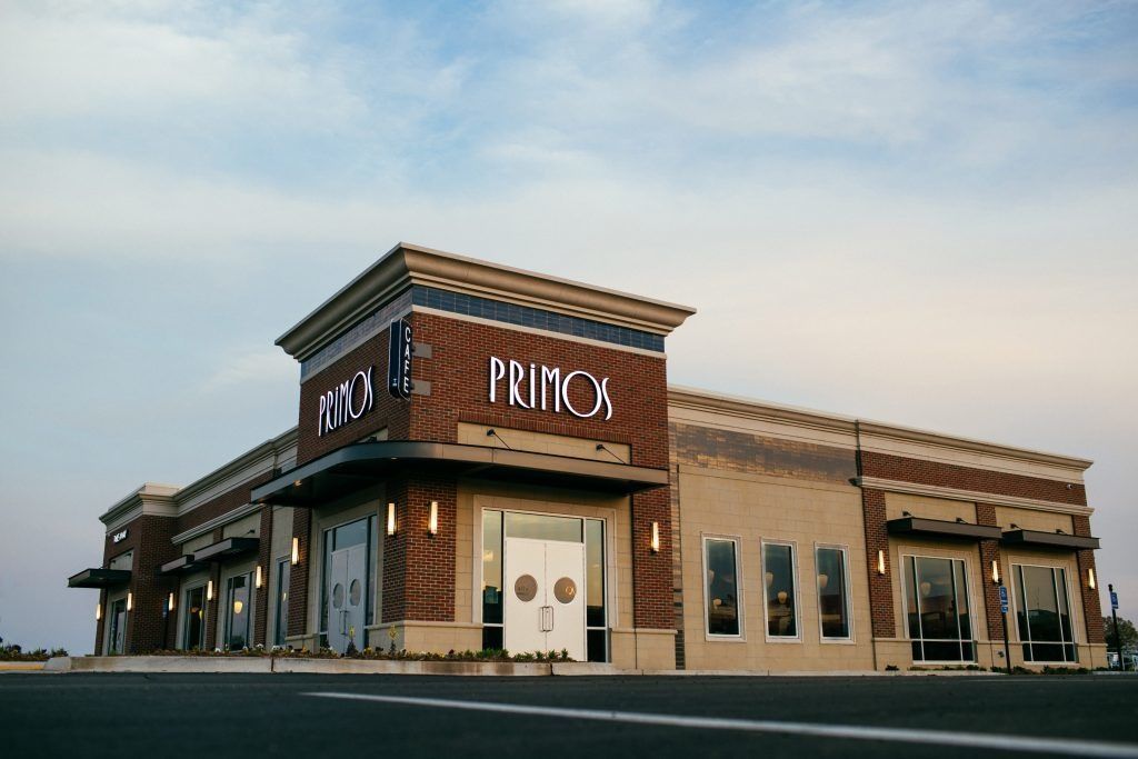 Primo's restaurant exterior with brick and tan walls, large sign, and windows, against a light blue sky.