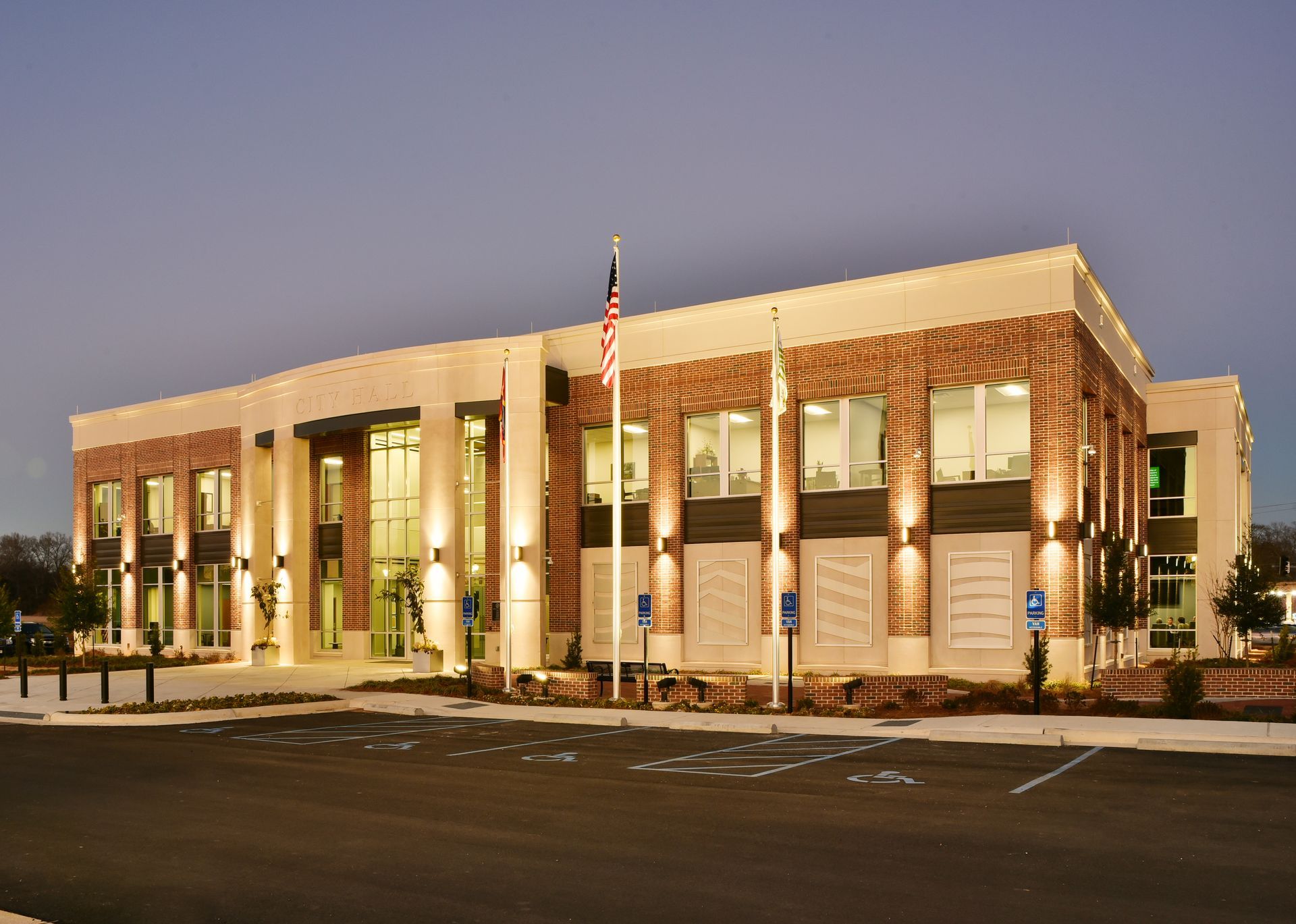 Three-story brick and cream-colored building with large windows and an American flag in front.