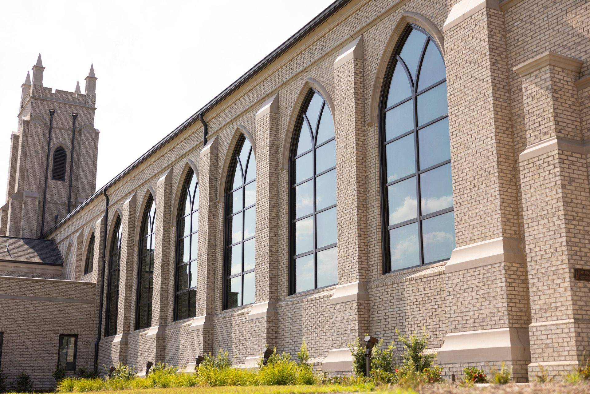 Brick church with tall arched windows and a tower.