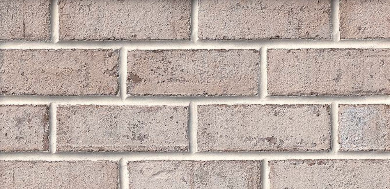 Close-up of a brick wall with light brown bricks and white mortar.